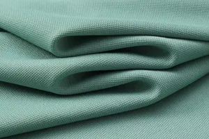 Close-up detail of breathable ice silk polo shirt fabric with teal honeycomb weave.