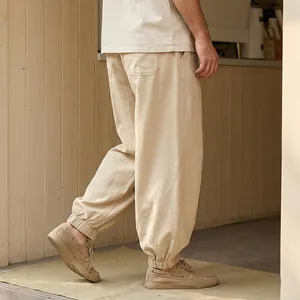 Detailed side view of men's loose beige linen jogger pants with elastic ankle cuffs