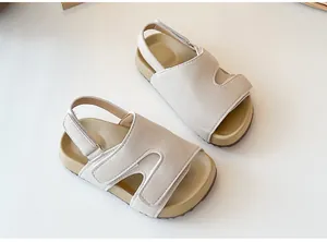 Ein Paar beige Kinder-Sandalen mit verstellbaren Klettverschlüssen auf weißem Grund