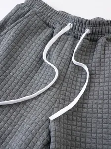 Detailed close-up of gray waffle grid shorts showing elastic waistband and drawstring