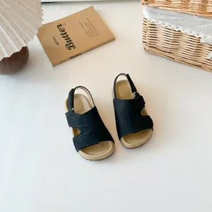 Schwarze Kinder-Sandalen im Birkenstock-Stil auf cremefarbenem Hintergrund