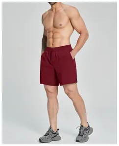 A fit male model wearing burgundy quick-dry athletic shorts shown in a studio side view