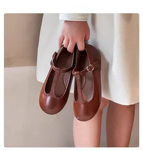 Close-up of children's vintage brown T-strap Mary Jane leather shoes held by a child