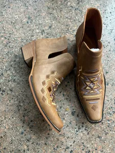 Gros plan de bottines Chelsea marron style western avec broderie géométrique détaillée.