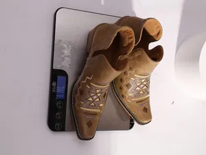 Gros plan de bottines Chelsea brodées marron pesées sur une balance numérique précise