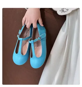 Close-up view of vintage sky blue T-strap Mary Jane shoes for young girls held by hand