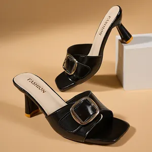 Black leather high-heeled mules with square toe and golden belt buckle detail