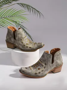 Détail de bottines Chelsea grises pour femmes avec broderie et talon en bois.