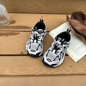 Gros plan de baskets respirantes noir et blanc pour enfants sur une terrasse en bois clair