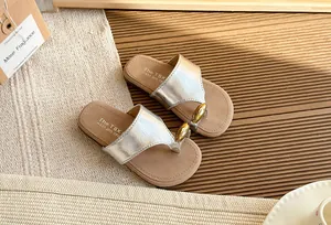 Chanclas plateadas de mujer con elegante detalle dorado, ideales para la playa en verano.