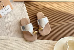 Vista detallada de sandalias de dedo plateadas metalizadas con un elegante adorno dorado