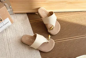 Detalle de sandalias de plataforma beige con un adorno de metal dorado de estilo sofisticado.
