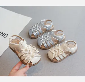 Nahaufnahme von süßen Mädchensandalen mit Schleifendesign in Silber- und Beigetönen