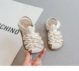 Nahaufnahme weißer Kleinkindsandalen mit süßen Schleifen und praktischem Klettverschluss