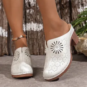 Detailed view of white closed-toe wedge mules with intricate laser-cut floral patterns