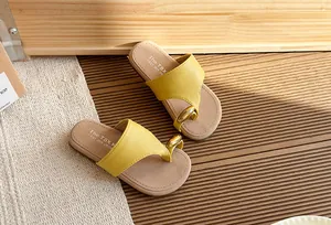 Sandalias amarillas estilo hada con detalle metálico dorado sobre suelo de madera