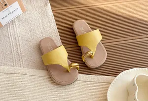 Detalle de sandalias de dedo amarillas con aro dorado y suela gruesa para verano