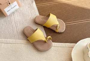 Primer plano de sandalias amarillas de dedo con adorno de anillo dorado en estera