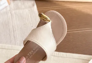 Primer plano de sandalia beige de dedo con un elegante detalle metálico dorado