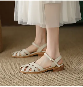 Detail view of cream woven leather sandals with adjustable ankle strap and low block heel