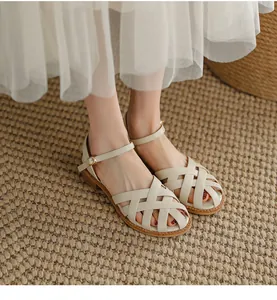 Detail view of stylish retro beige woven leather sandals with ankle strap on model