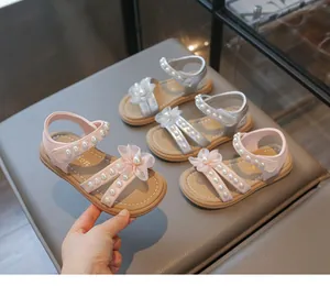 Detailansicht von rosa und silbernen Mädchensandalen mit Perlen und Blumenakzenten