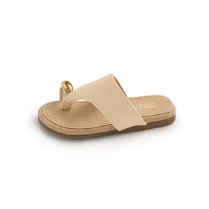 Elegant beige thong sandals with a gold pebble ornament on a minimalist white background