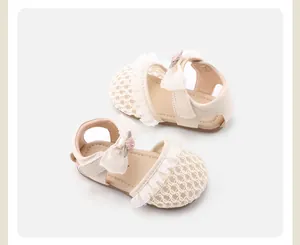 Draufsicht auf cremefarbene Baby-Sandalen mit eleganter Spitzenschleife und Blumendetails