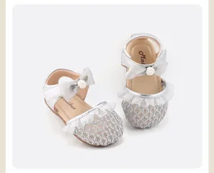 Detailaufnahme silberner Baby-Mädchen-Sandalen mit feinem Spitzenbesatz und Schleife
