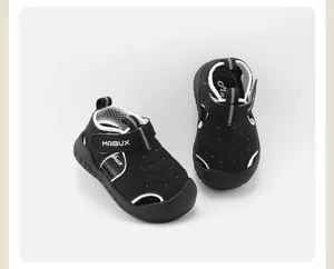 Vista detallada de sandalias negras para niños pequeños con ribete blanco y logo MAIBUX