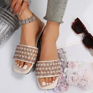 Detail shot of elegant flat slippers featuring decorative pearls and sparkling rhinestones