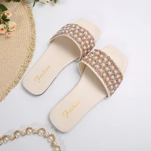 Close-up detail of beige summer flat slides with elegant pearl and rhinestone strap