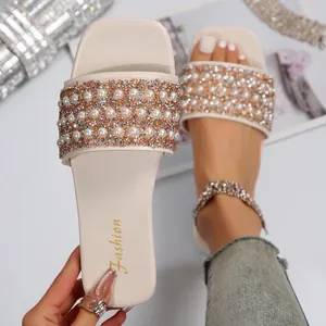 Close-up detail of women's off-white flat slides with pearls and crystals decoration