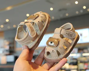 Close-up of baby boy sandals featuring a cute cartoon bear and paw print cutouts