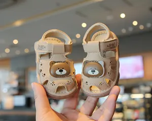 Close-up of cute cartoon bear baby sandals with soft non-slip soles in beige