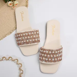 Detailed macro view of women's flat sandals with elegant pearls and sparkling rhinestones