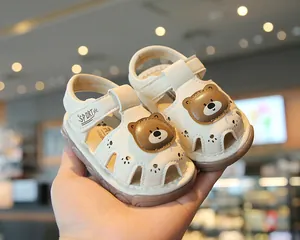 Detail view of cute cartoon bear patch on beige closed-toe baby walking sandals