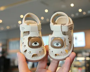 Close-up of beige baby sandals with a cute brown bear cartoon on the front