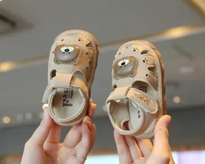 Close-up of beige toddler sandals with cute cartoon bear and secure Velcro strap closure.