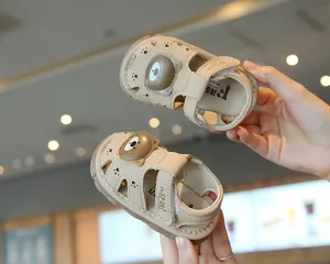 Detailed view of beige baby sandals with cute cartoon bear design and breathable holes