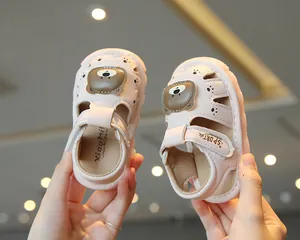 Close-up of cute pink bear baby sandals with soft soles and closed-toe design