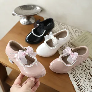 Detail view of elegant pink girls' patent leather Mary Janes with pearl and bow accents