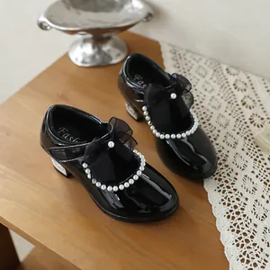Close-up detail of girls black patent leather Mary Jane shoes with pearl and bow