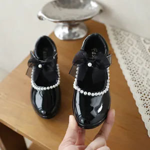 Detailed view of girls' black patent leather Mary Jane shoe with pearls and bow