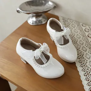 Close-up of white girl's princess shoes with pearl trim and delicate bow detail