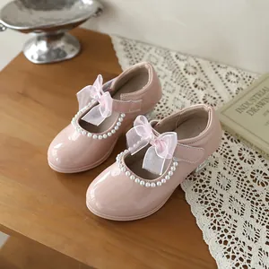 Detailed macro view of pink girls' Mary Jane shoes with elegant pearl trim and ribbon bow