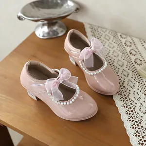 Close-up of elegant pink patent leather girl's princess shoes with pearls and lace bow knot