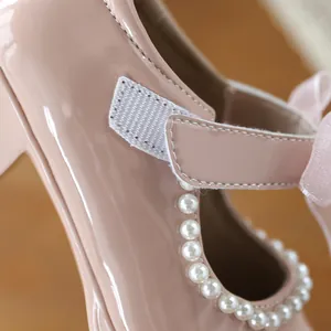Close-up of pink patent leather girls' shoes featuring elegant pearl trim and Velcro strap.