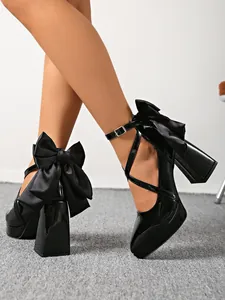 Elegant black pointed-toe block heels featuring cross straps and oversized rear bows
