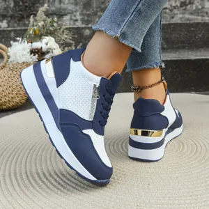 Vista dettagliata delle sneakers con zeppa blu navy e bianche con cerniera laterale e oro.